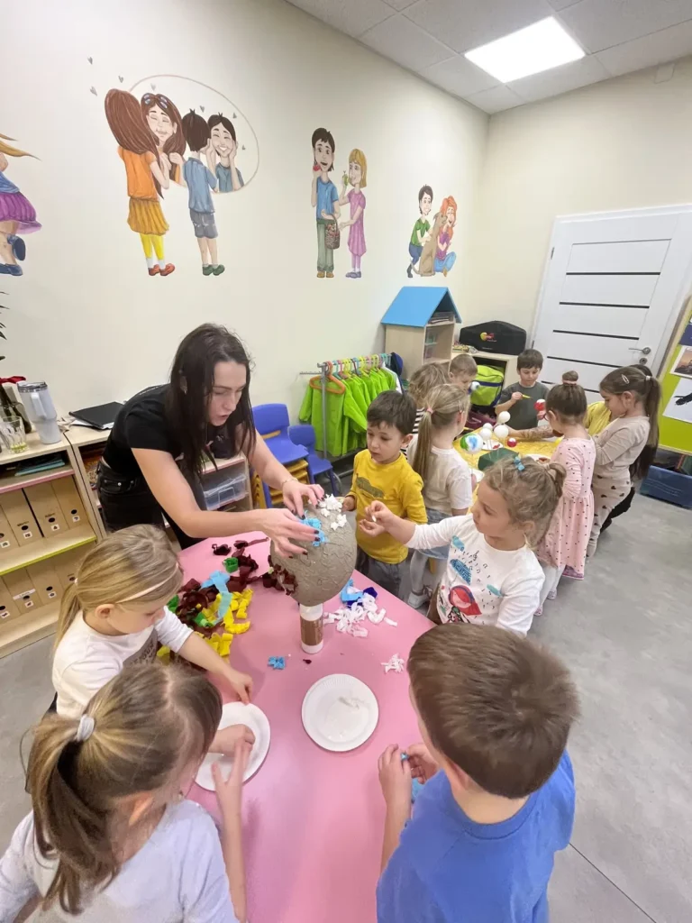 Deti zo súkromnej materskej školy PrimaKids tvoria kreatívny projekt s učiteľkou počas výtvarnej aktivity v triede